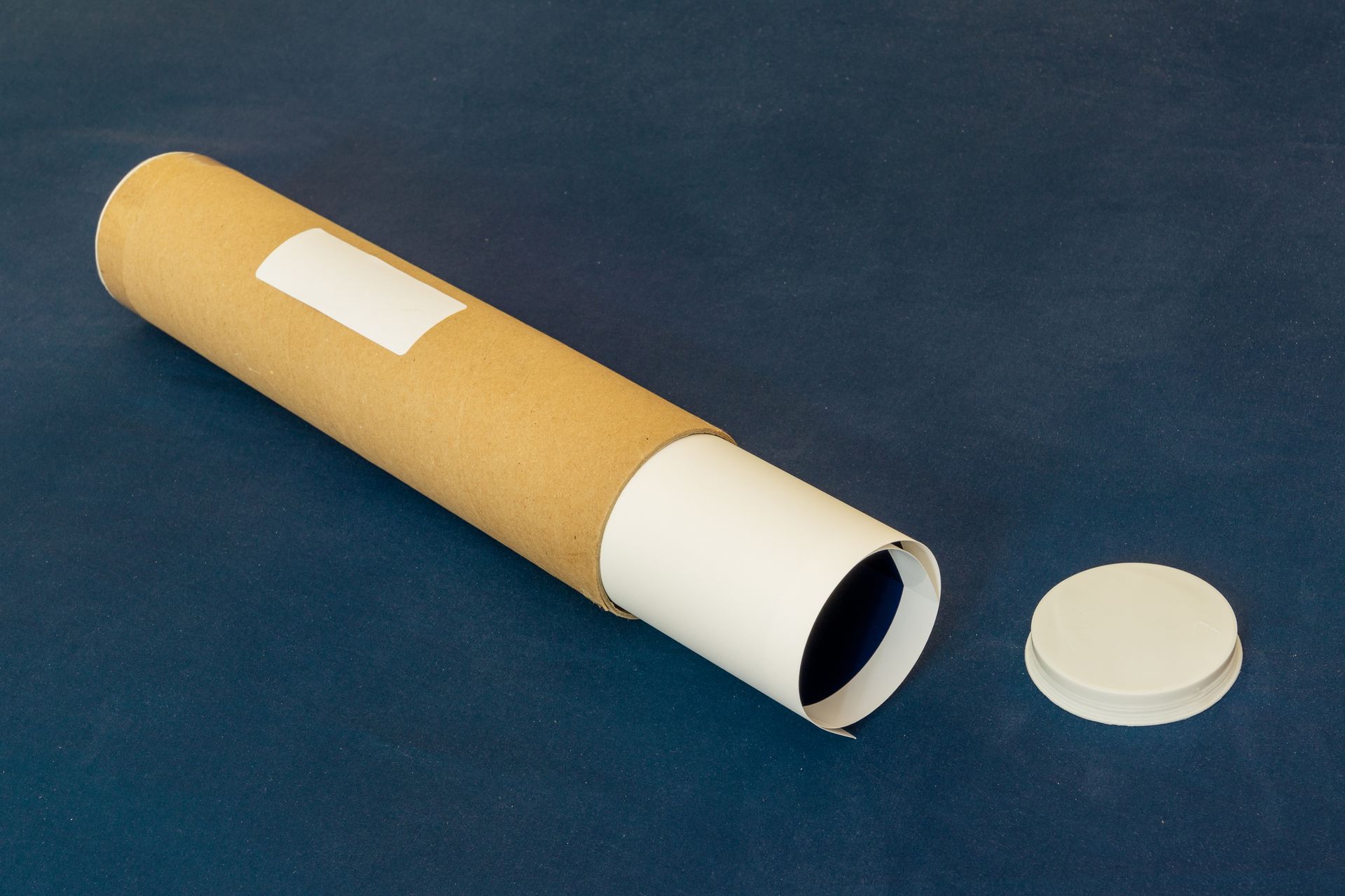 Cardboard tube with white label, lid off. Set on blue surface.