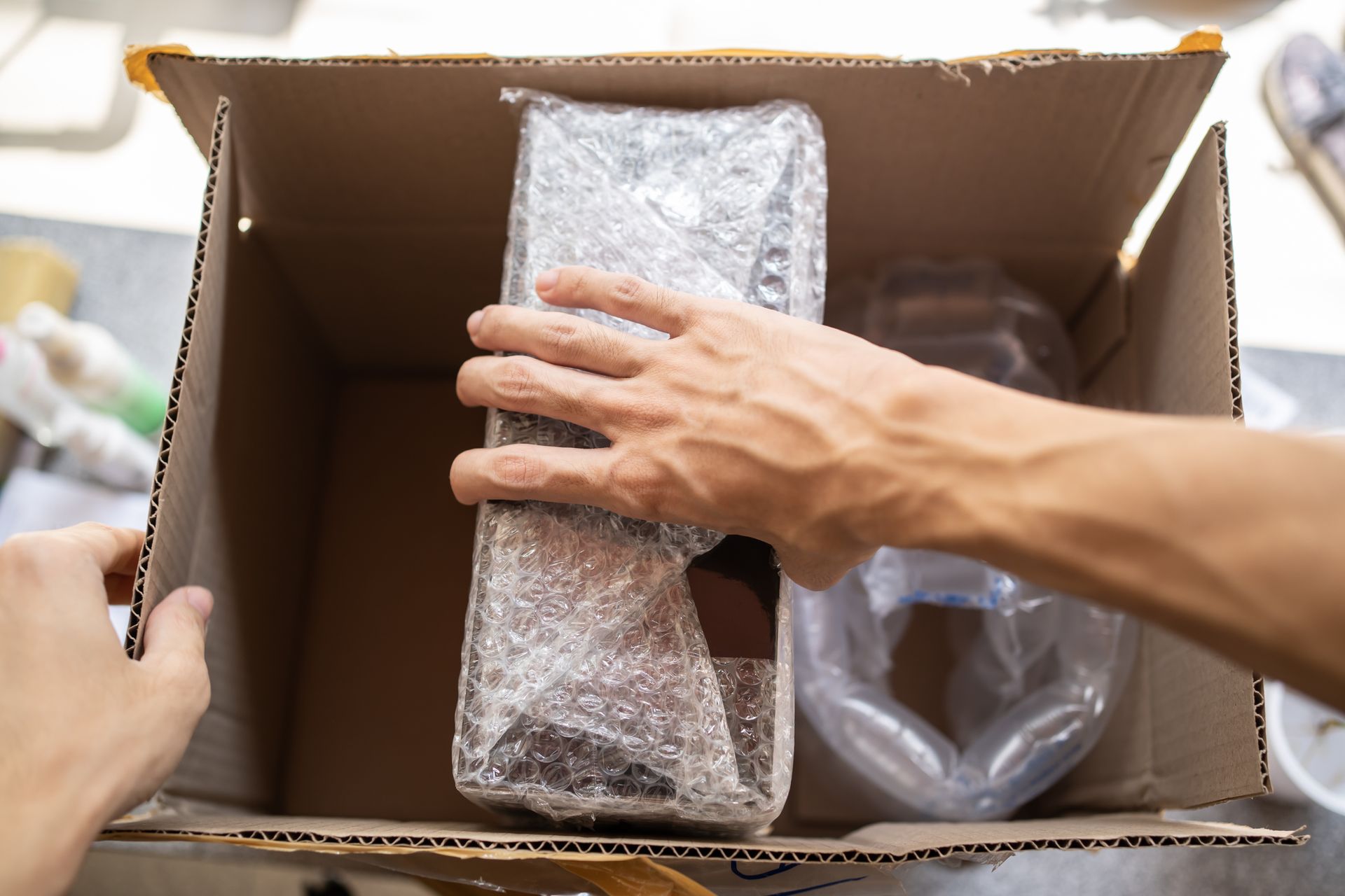 A person is putting something in a cardboard box.