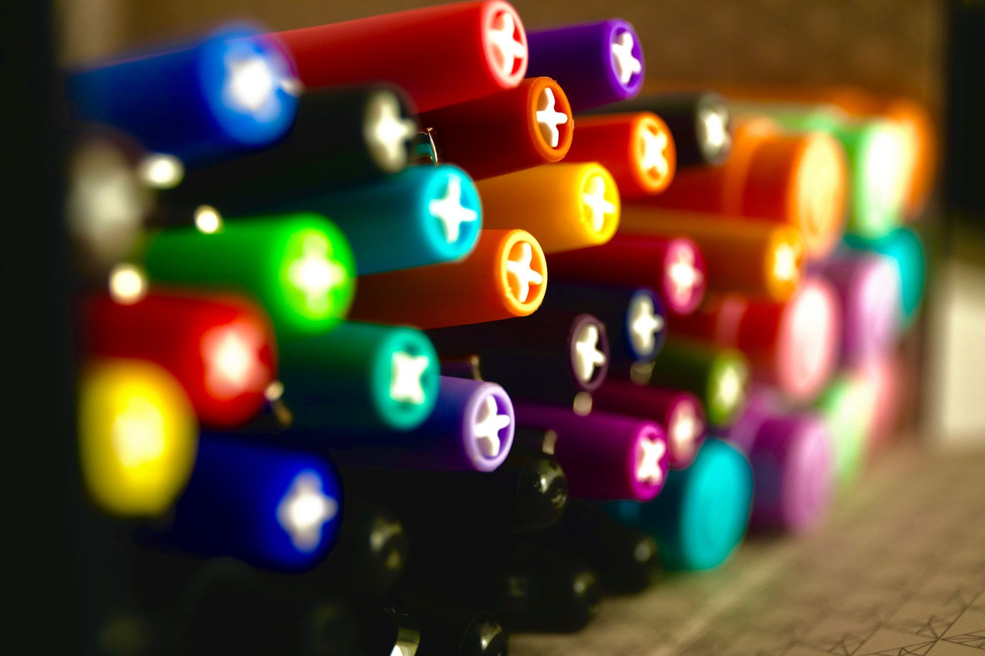 A bunch of colorful pens are stacked on top of each other on a table.