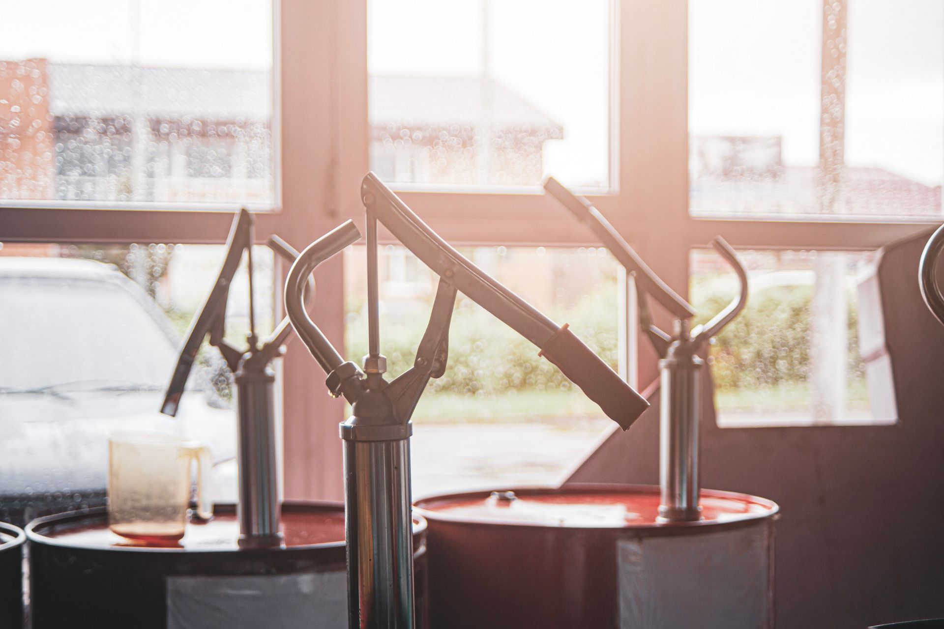 A group of oil pumps sitting on top of barrels in a garage.