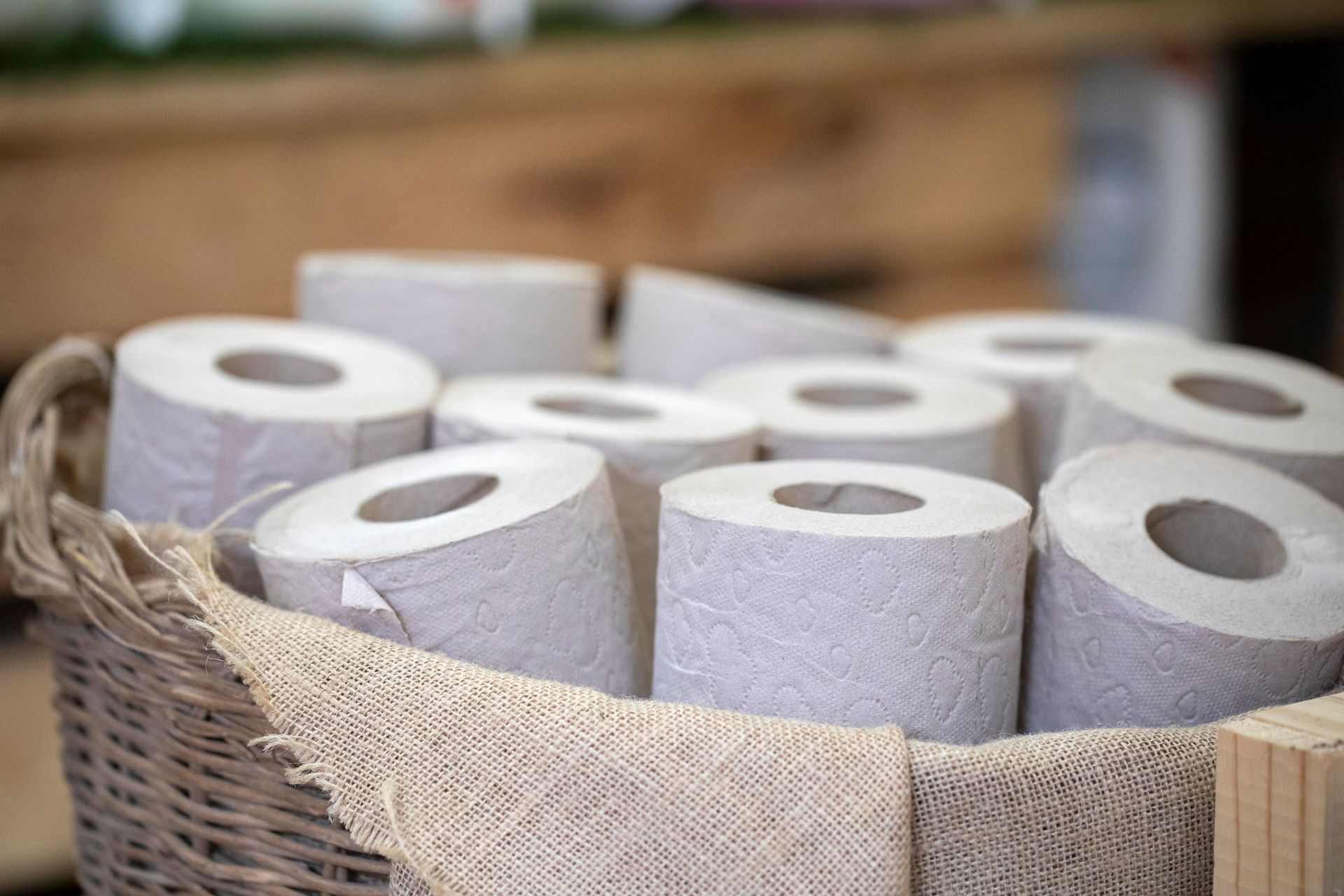 Basket filled with rolls of gray toilet paper.