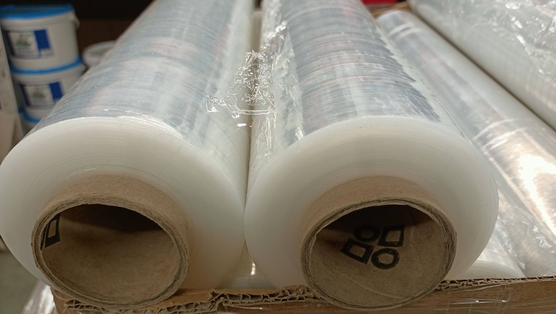 Two rolls of plastic wrap are sitting on top of a cardboard box.