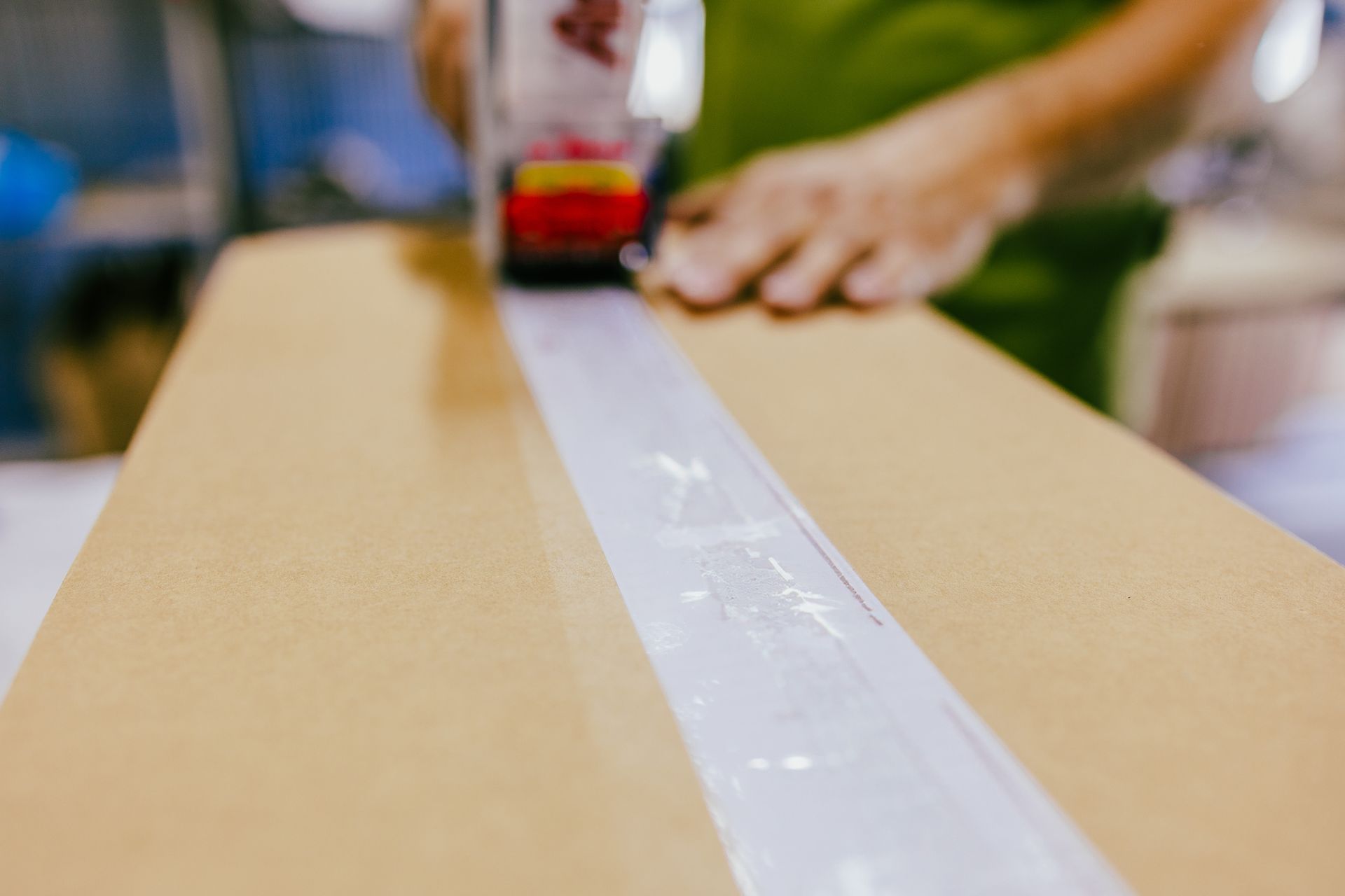 Person sealing a cardboard box with packing tape.