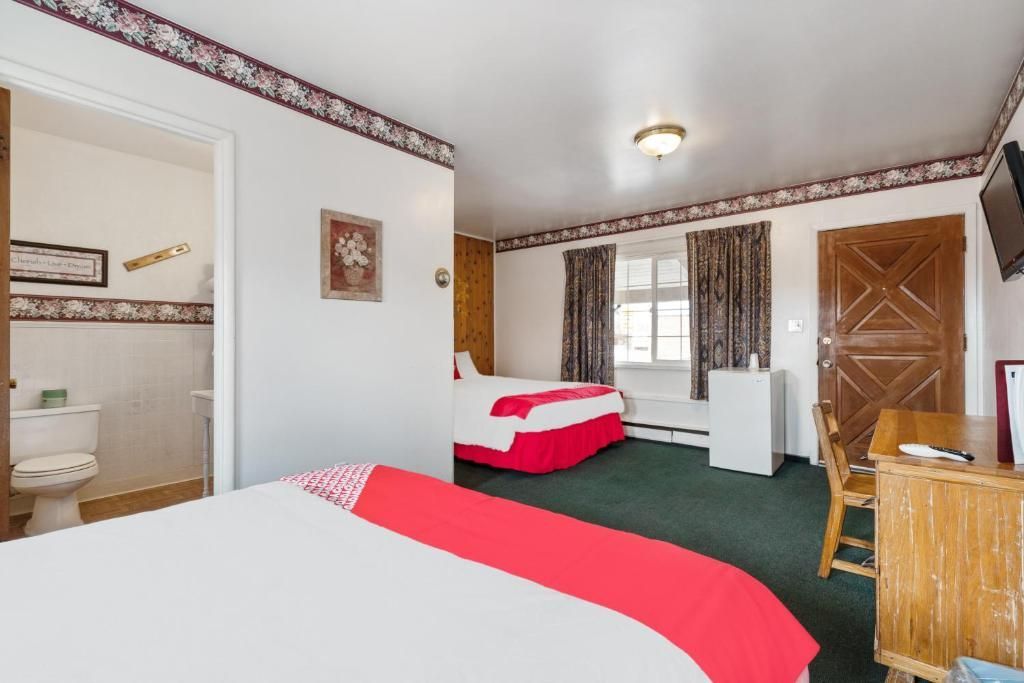 A hotel room with two beds , a desk and a television.