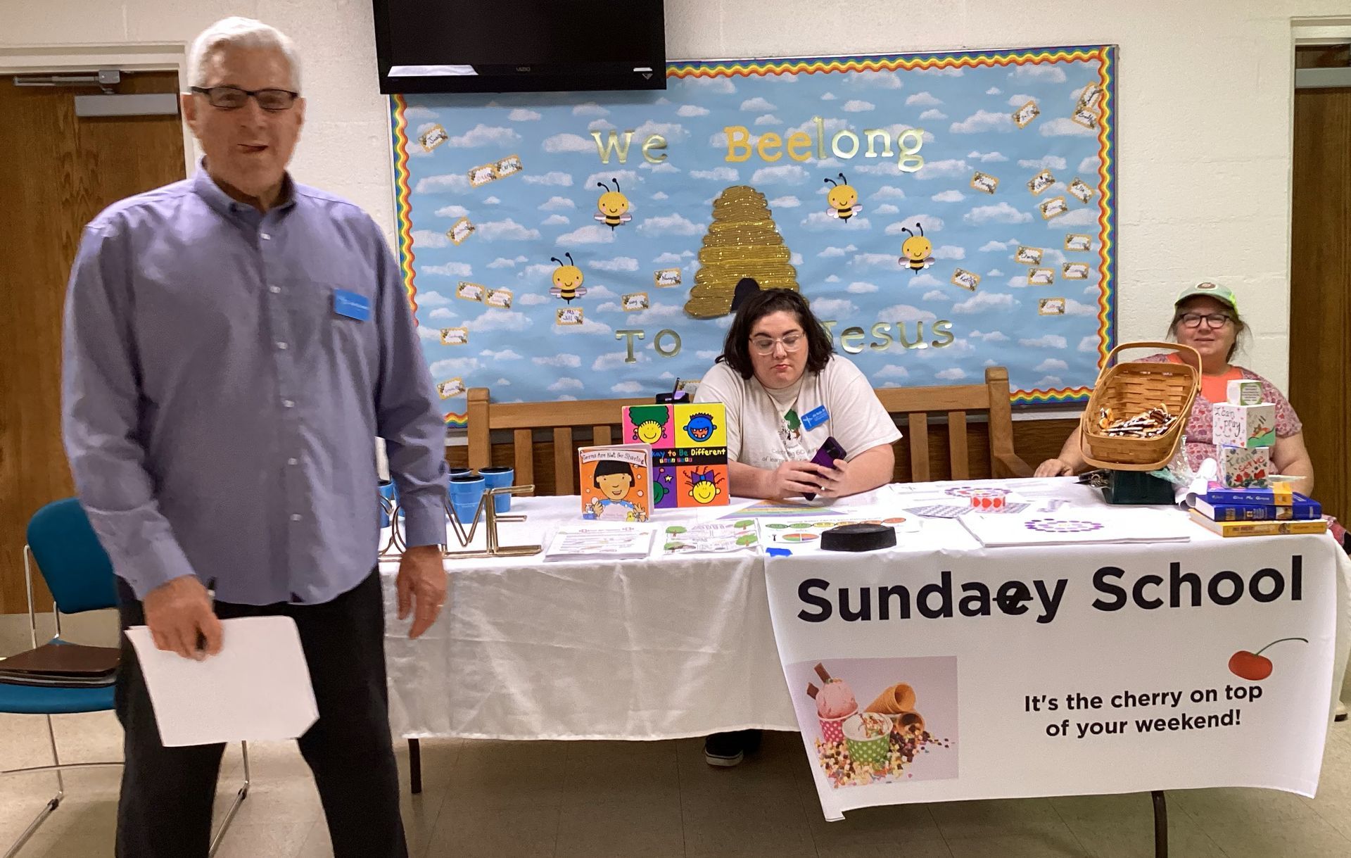 Man in a blue shirt stands near a table labeled 