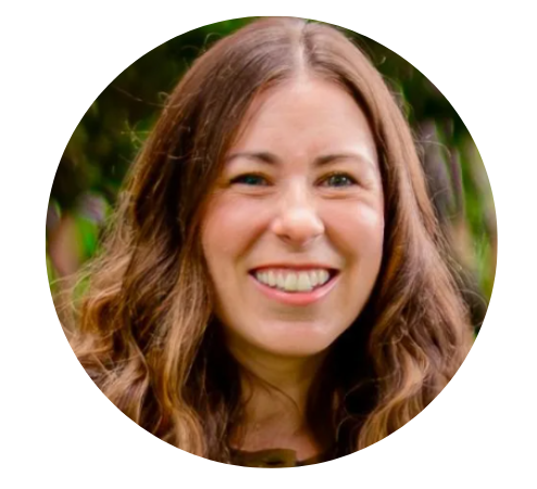 Woman with long brown hair smiles broadly at the camera, against a blurred green background.