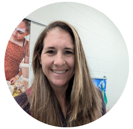 Woman with long brown hair smiling at the camera. She has blue eyes and is wearing a burgundy top.