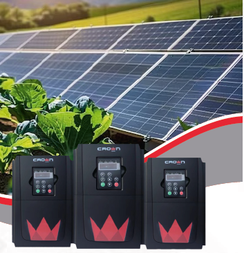 Solar panels behind three black Crown inverters, with a red crown logo, in a field.