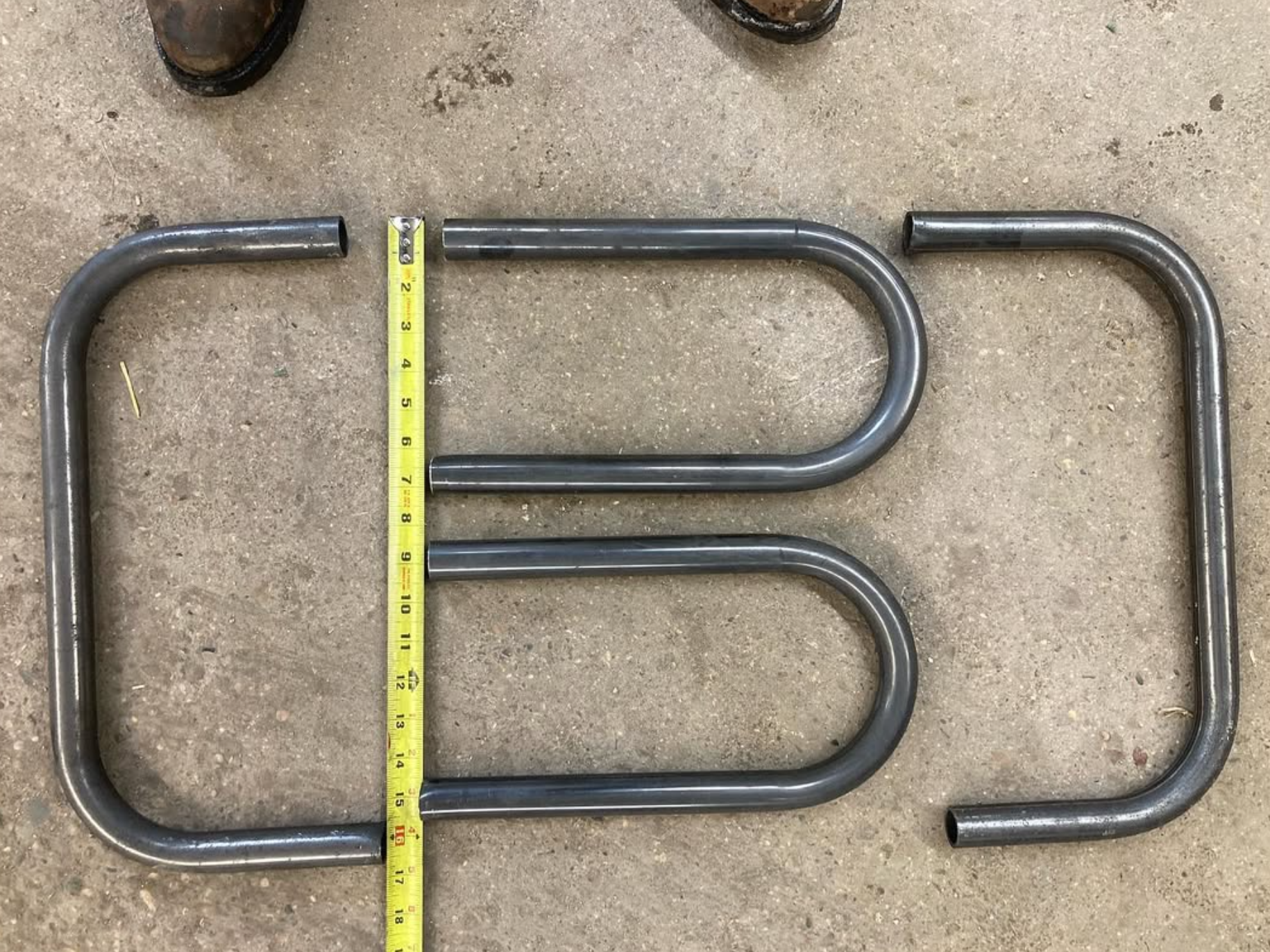 Three bent metal tubes arranged to resemble the letters