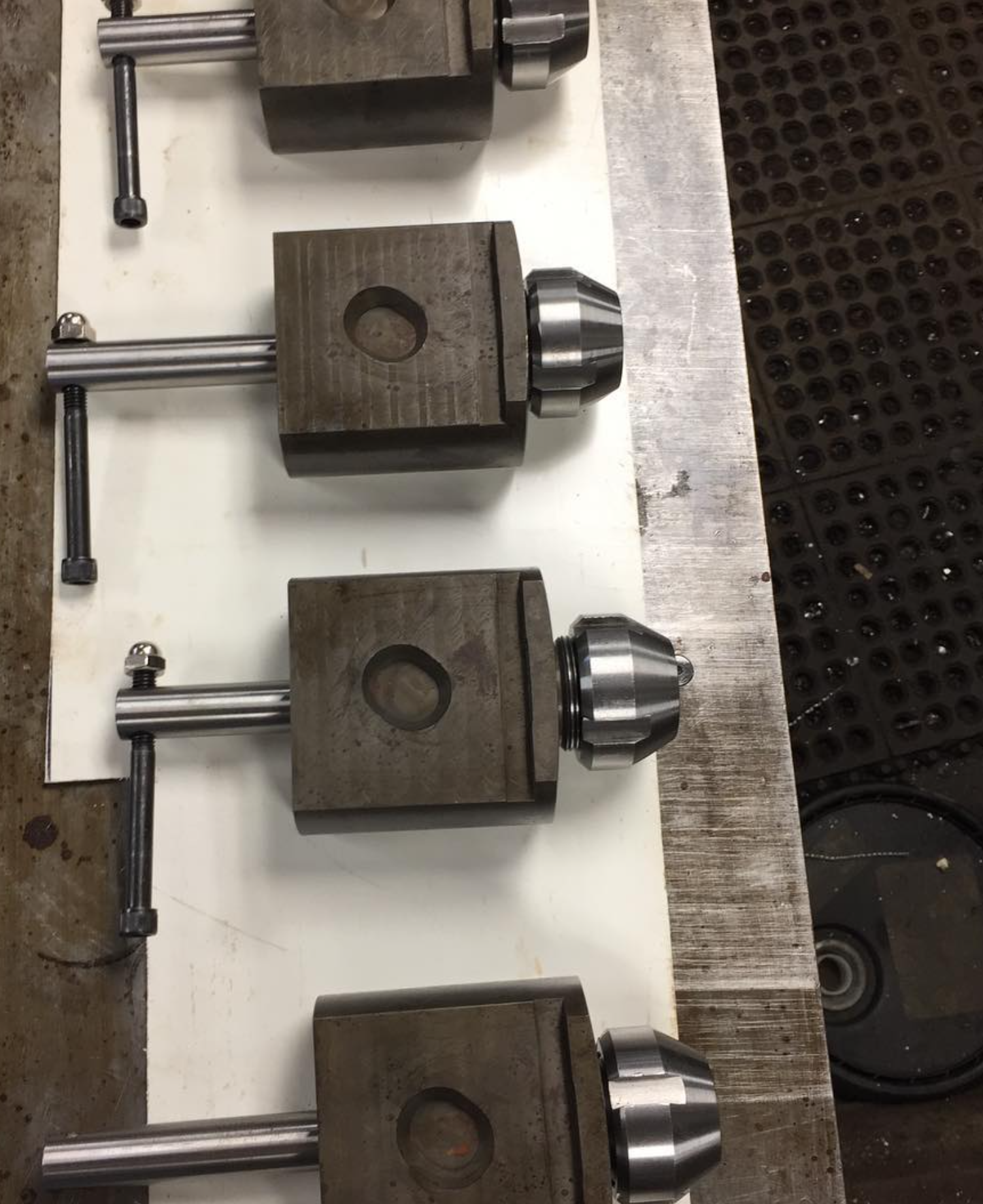 Four machine tool holders with chucks, arranged on a surface. Each has a handle and is dark metal.