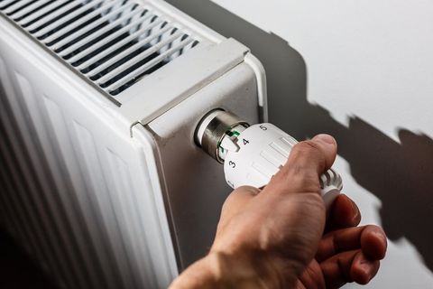 Close Up Of Hand Adjusting Heating Thermostat — Saddle Brook, NJ — Mazzone Plumbing Inc.