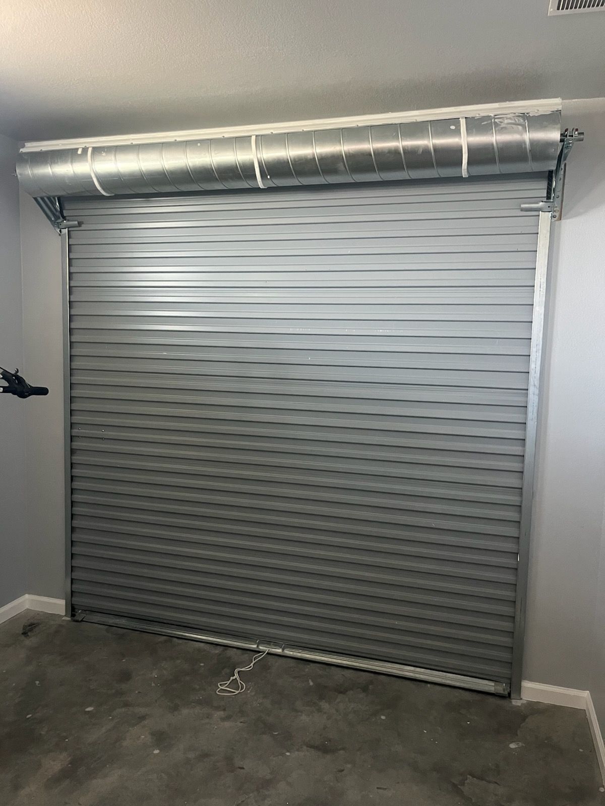 Loading dock with open industrial door, truck, yellow safety barriers, and warehouse interior.
