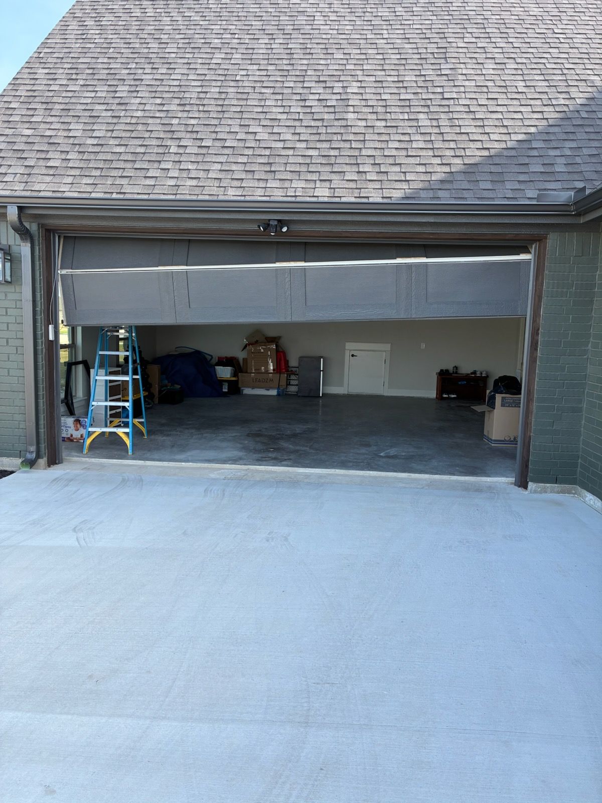 Empty, weathered loading dock. Stack of pallets to the left, closed garage door in center, exit sign above.