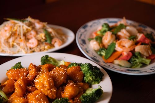 Three plates of food are sitting on a wooden table.