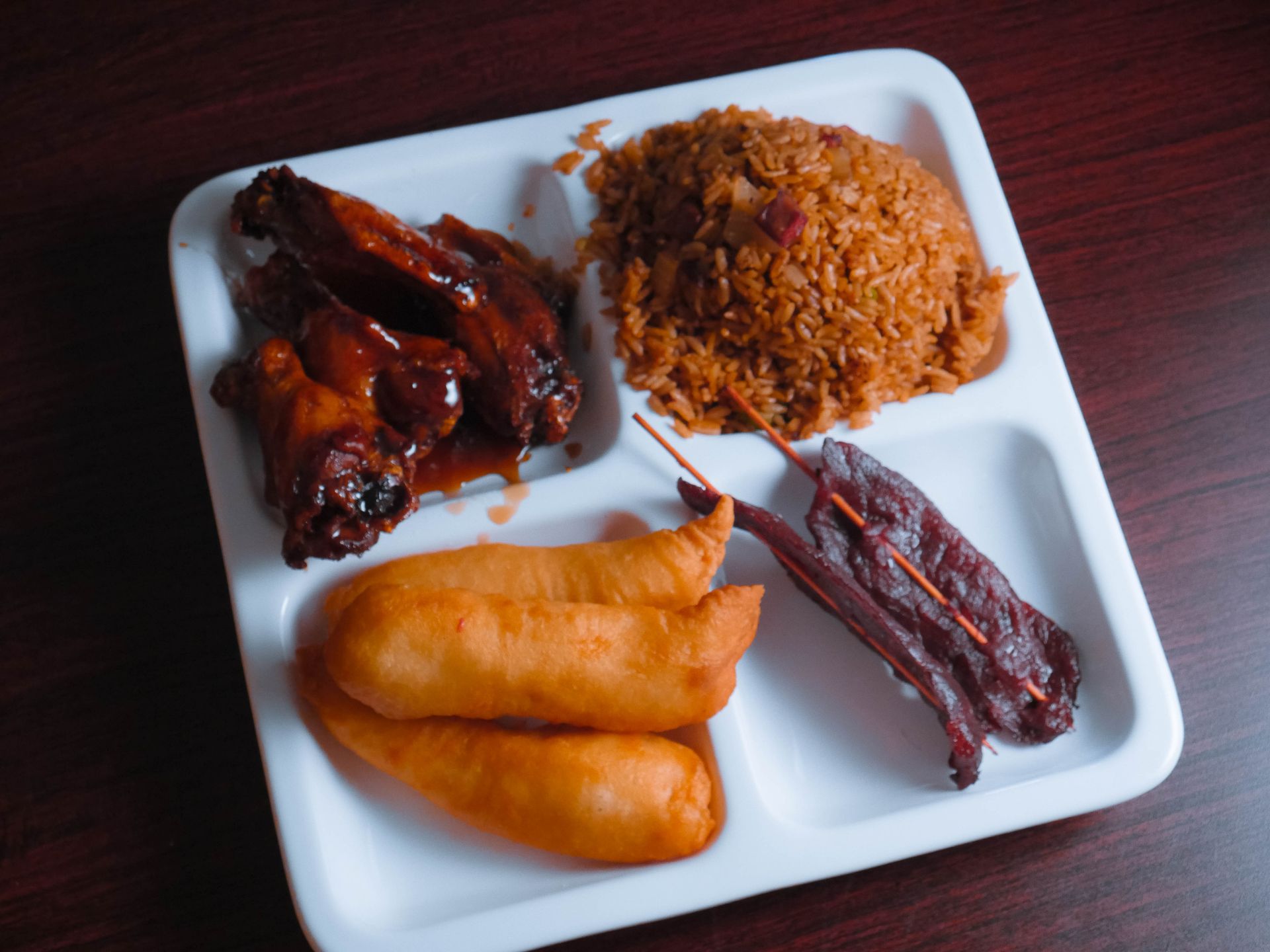 A tray of food includes fried rice chicken wings and bacon