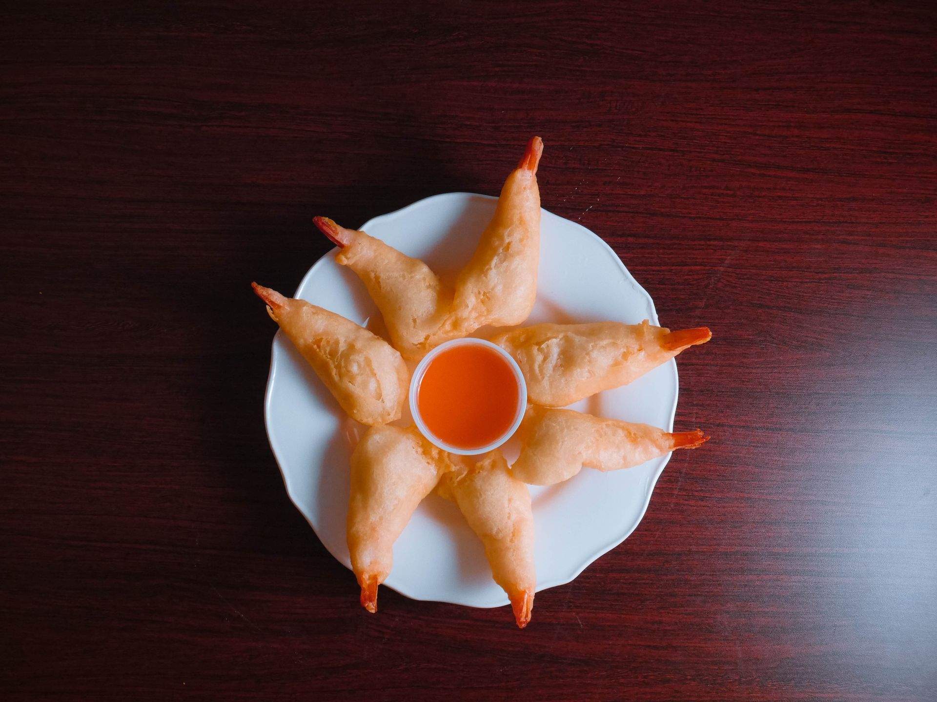 A white plate topped with shrimp and sauce on a wooden table.