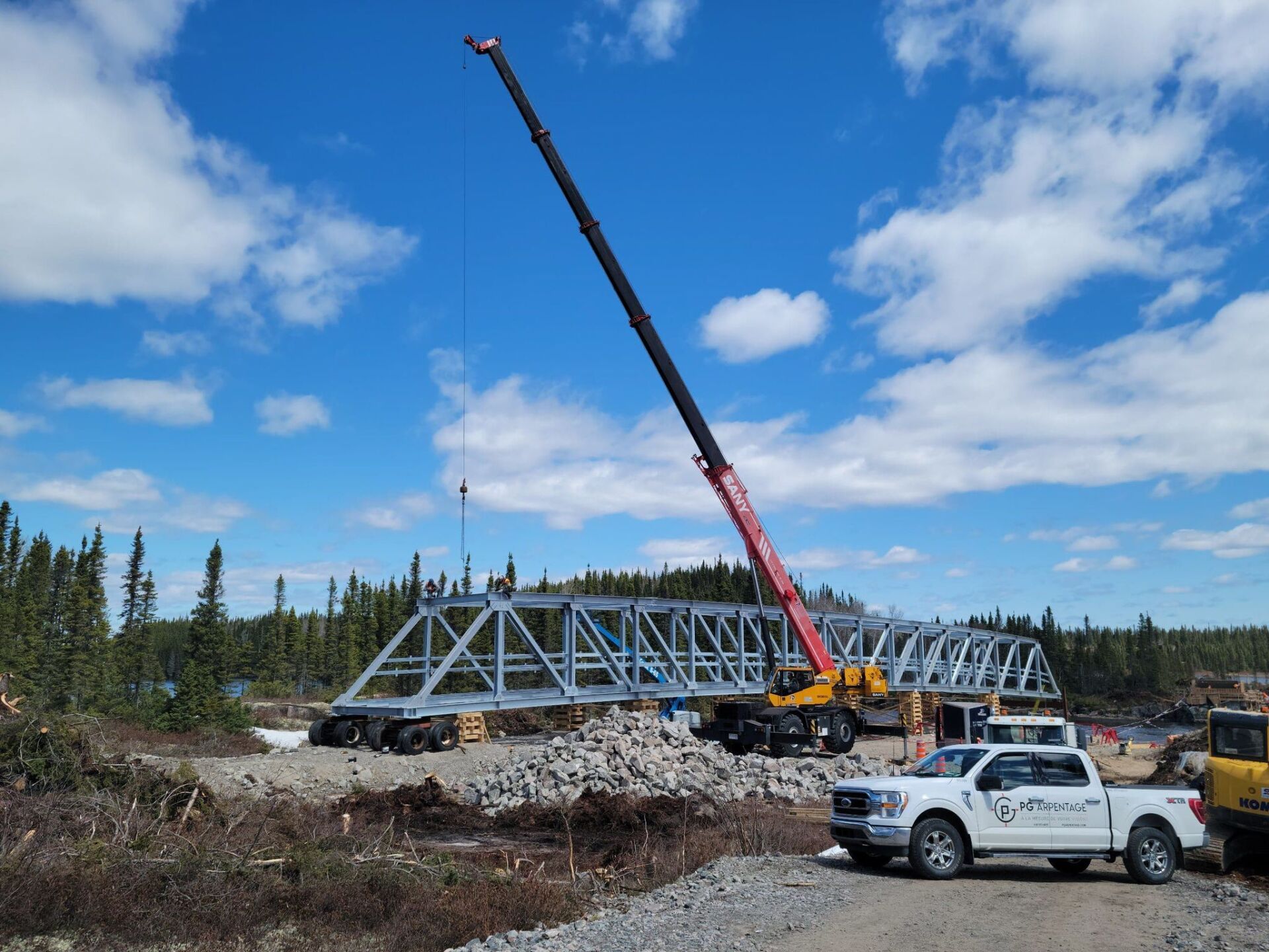 A white truck is parked in front of a bridge being built