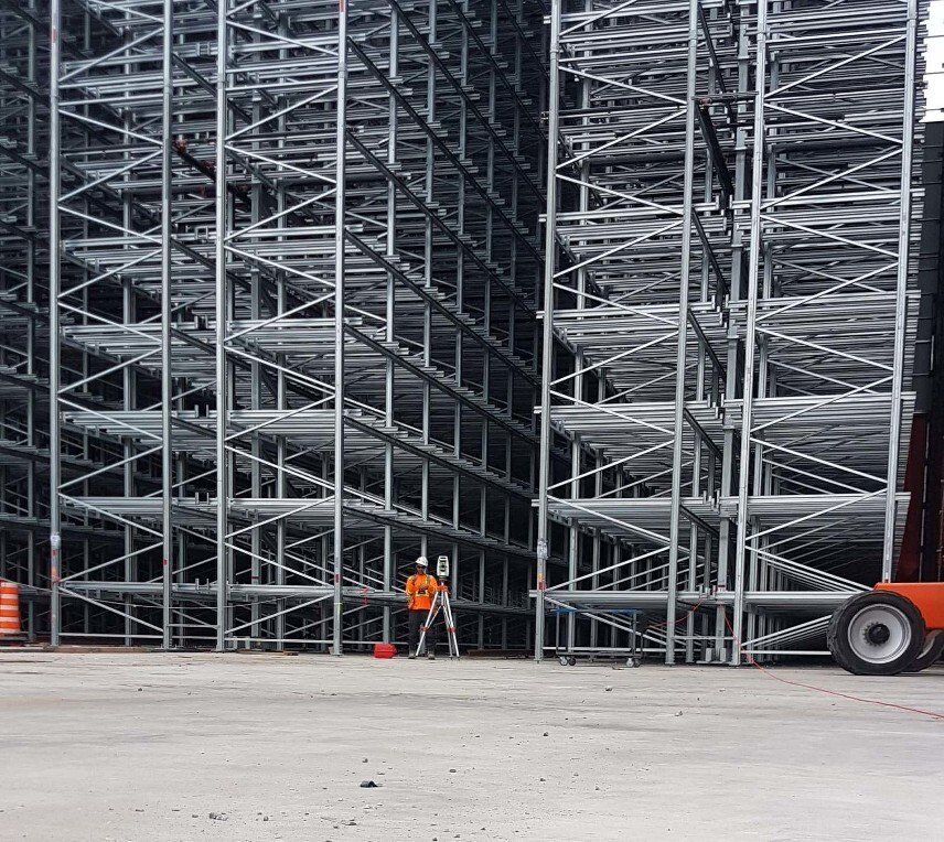 Un grand entrepôt avec beaucoup d'étagères et un chariot élévateur garé devant.