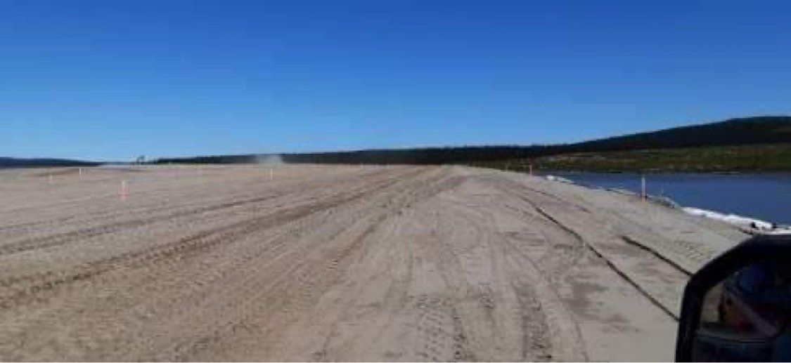 Une personne conduit sur un chemin de terre à côté d'un plan d'eau.