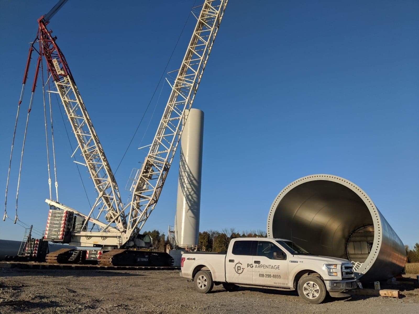 Un camion blanc est garé devant une grande grue.