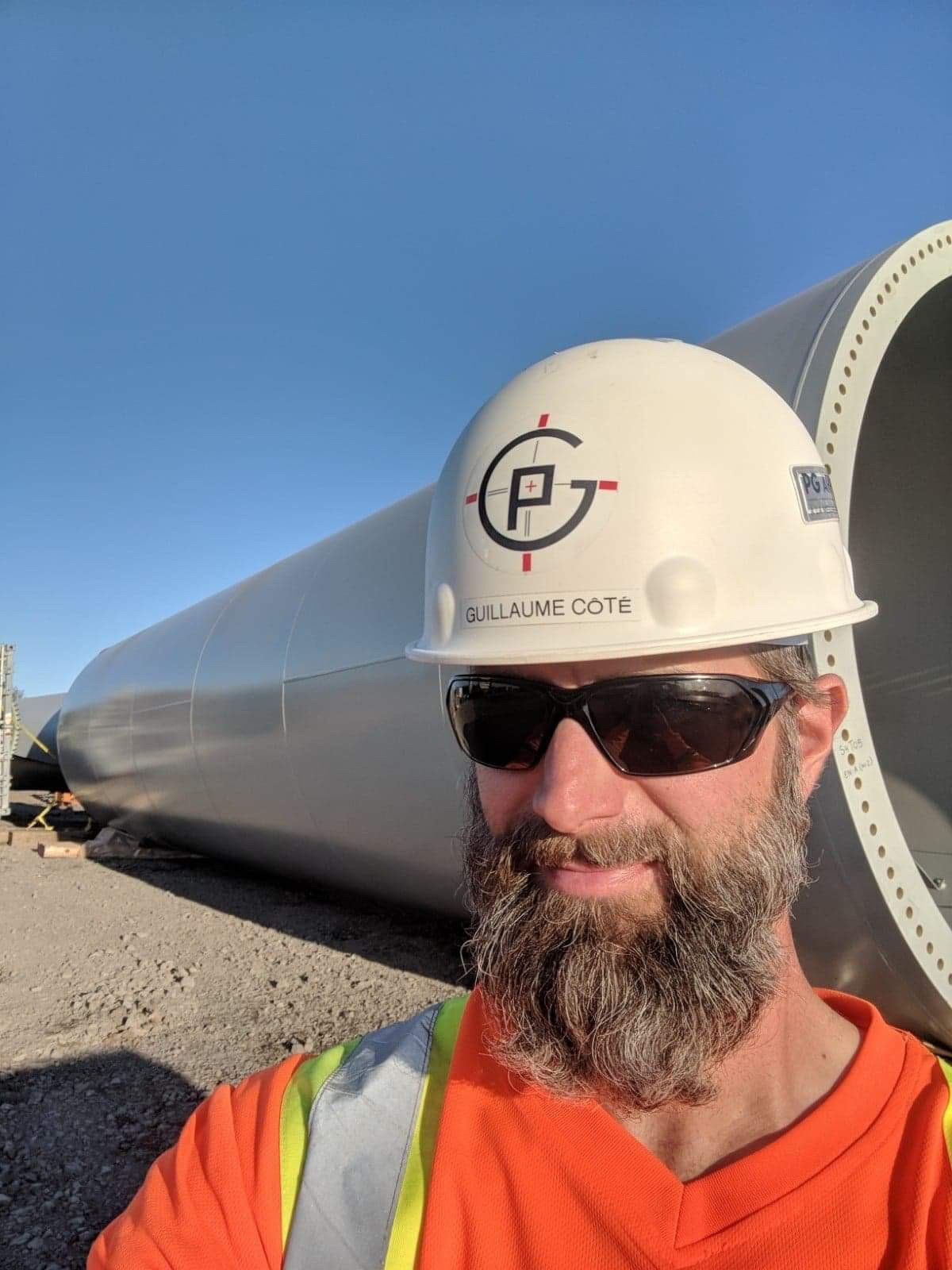 Un homme avec une barbe porte un casque et des lunettes de soleil.