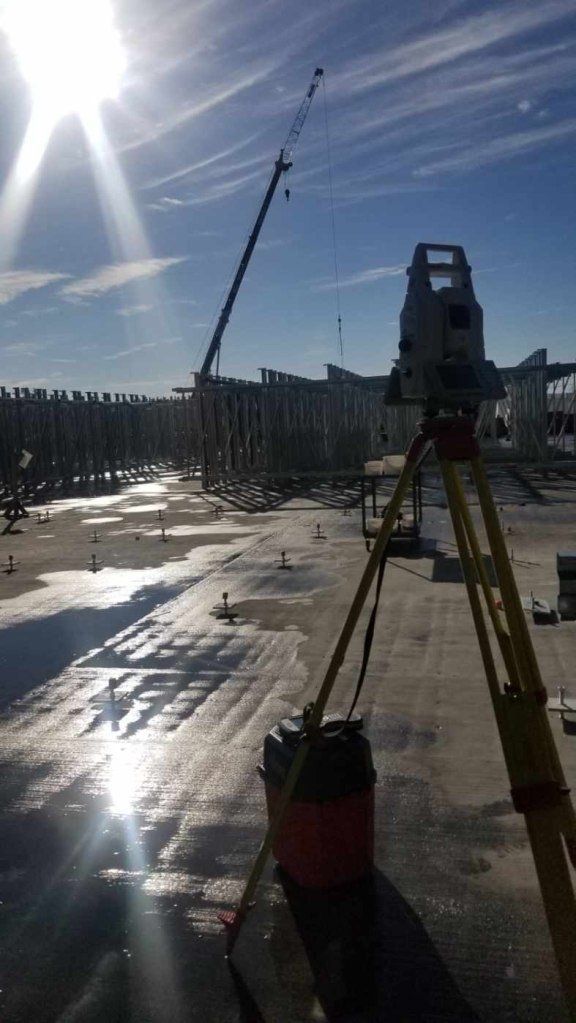 Un chantier de construction avec une grue en arrière-plan et le soleil qui brille à travers les nuages.