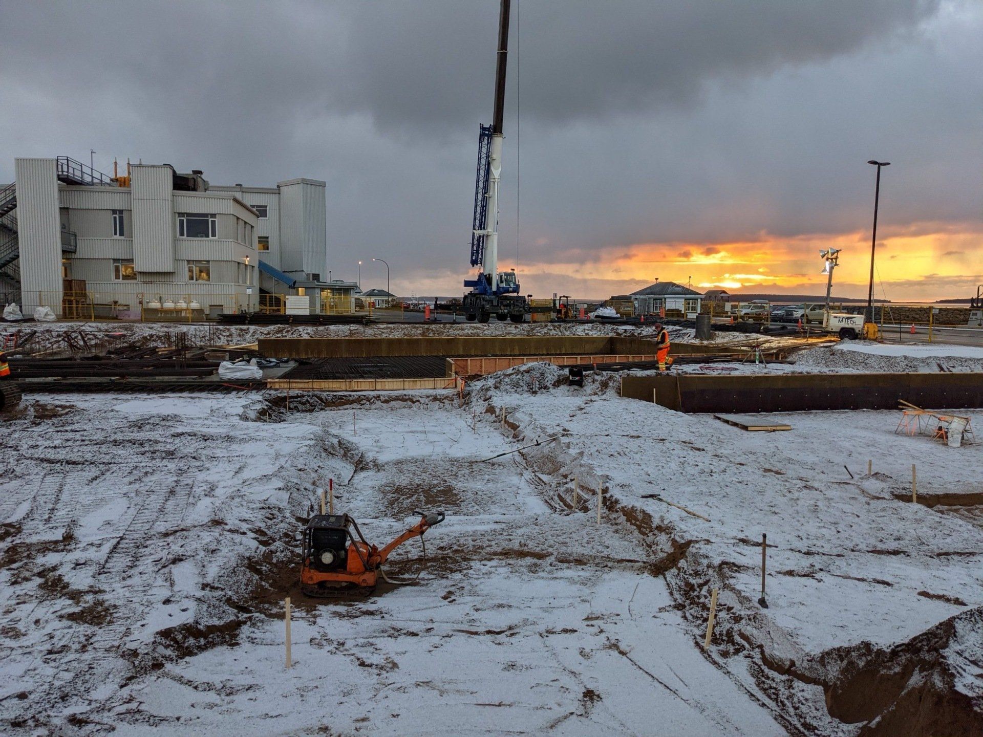 Un chantier de construction avec de la neige au sol et un bâtiment en arrière-plan