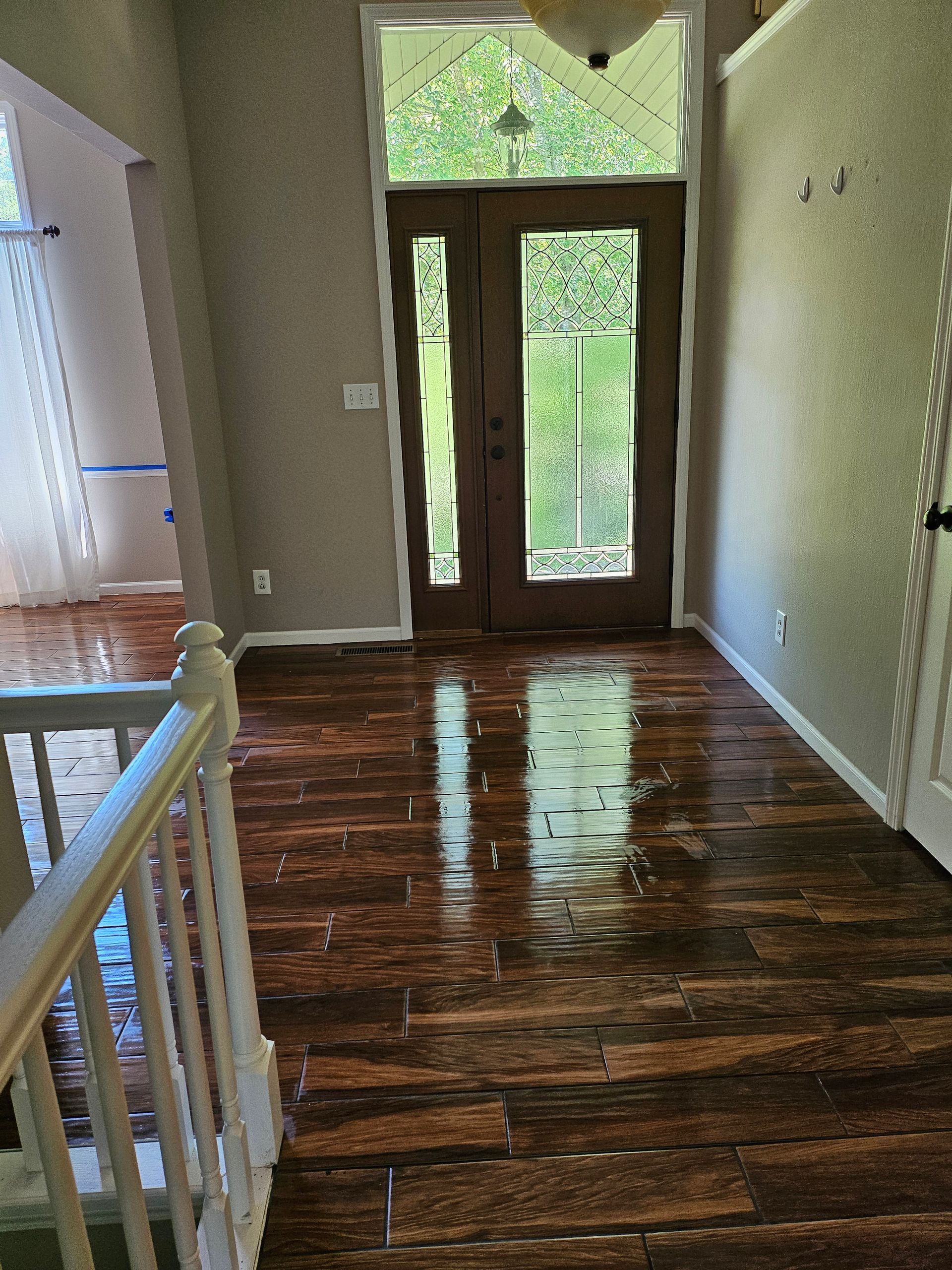 A hallway with hardwood floors and a staircase leading to a door.