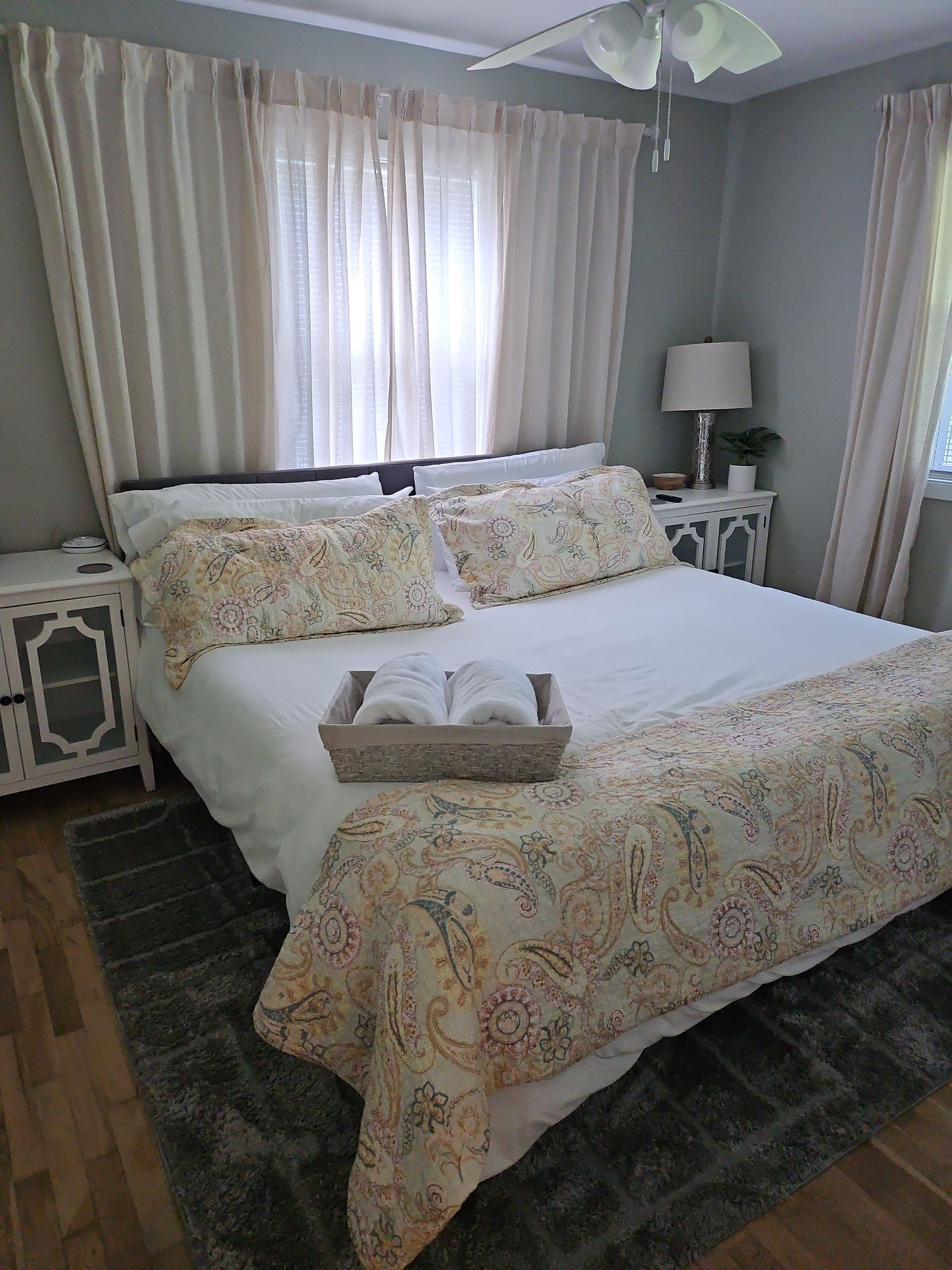 A bedroom with a bed , nightstand , lamp and window.