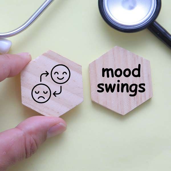 Hand holding a wooden hexagon with a sad-to-happy face symbol next to one that says