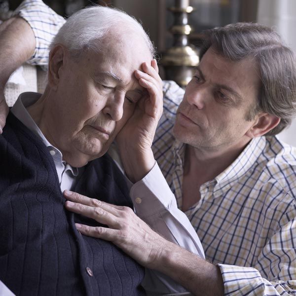 An older man with his hand on his forehead, supported by a man with his arm around him. Both in a room, somber expressions considering Complementary and Functional Alzheimer's Disease Medical Treatments by Salerno Wellness in Manhattan, NY, and Connecticut