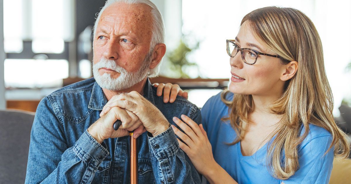 An elderly man with a concerned expression, comforted by a young woman, hand on his shoulder, considering Alzheimer's Disease Treatments NYC by Dr. John Salerno