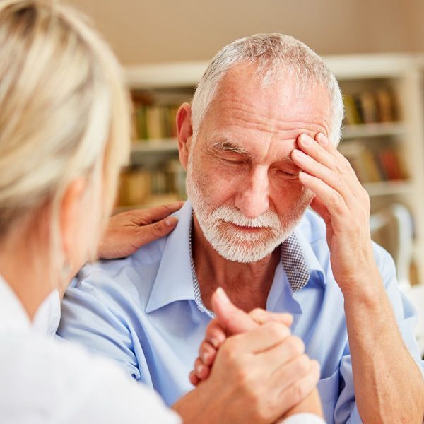 A man with a beard is being comforted by a woman. Alzheimer’s IV Treatments