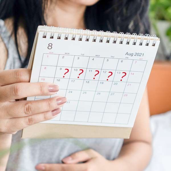 A woman is holding a calendar with red question marks on it representing Amenorrhea Treatments