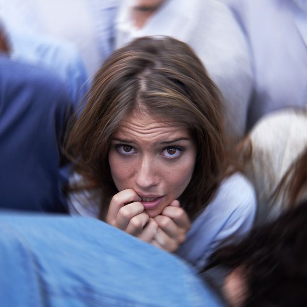 A woman is biting her nails in a crowd of people needing her Anxiety IV Treatments