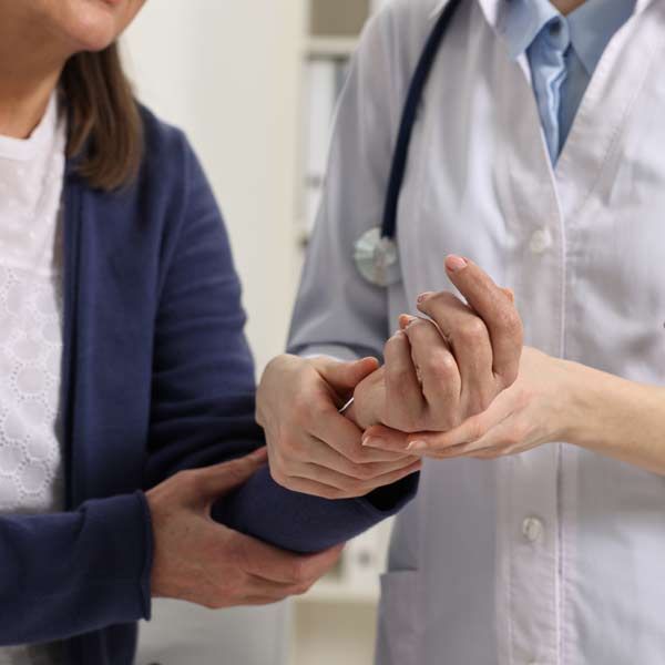 A doctor is examining a patient's wrist, recommending Arthritis IV Treatments