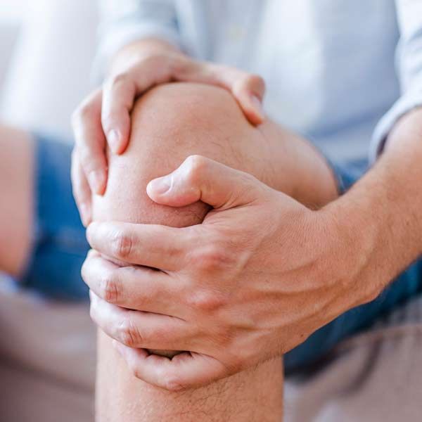 A person is holding their knee in pain in need of Innovative Arthritis Medical Treatments by Salerno Wellness in Manhattan, NY, and Connecticut