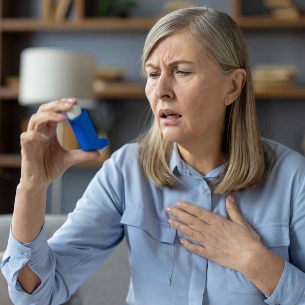 A woman is holding a blue inhaler in her hand, needing Asthma IV Treatments