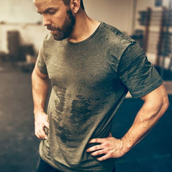 A man with a beard is standing in a gym with his hands on his hips after getting his Athletic IV Treatments