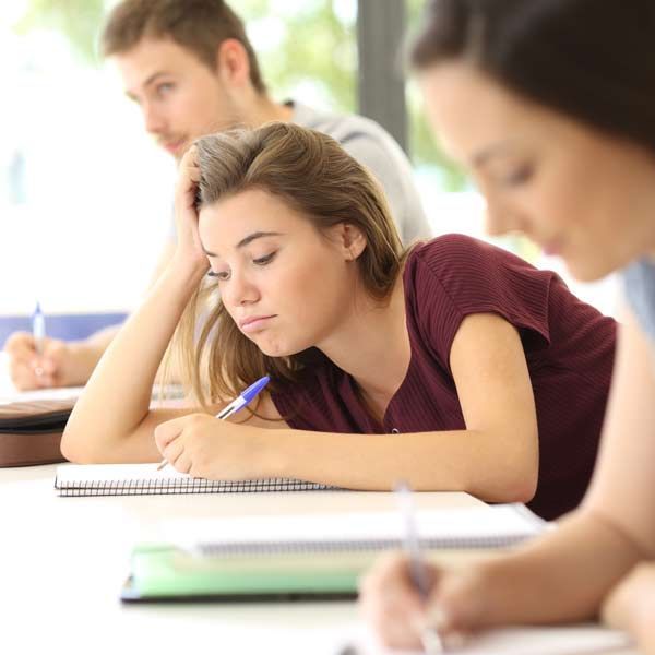 A group of students are sitting at a table writing in notebooks representing Attention Deficit Disorder Treatments