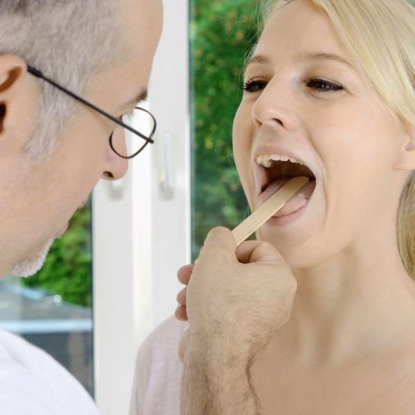 A woman is getting her throat examined by a doctor for Complementary, Integrative, and Functional Medical Treatments for Barrett's Esophagus Disease by Salerno Wellness in Manhattan, NY and Connecticut