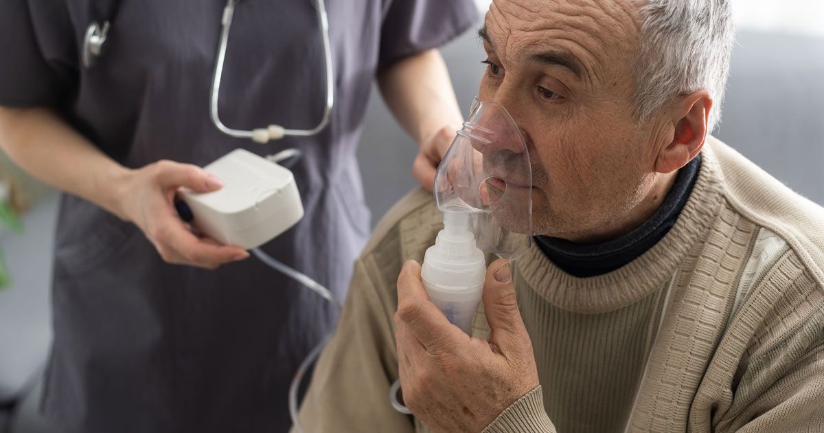 An elderly man is getting an oxygen mask from a nurse while at COPD Treatments NYC by Dr. John Salerno