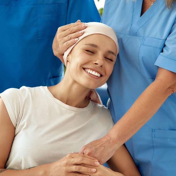 A woman with cancer a bandana on her head is smiling after her Cancer IV Treatment