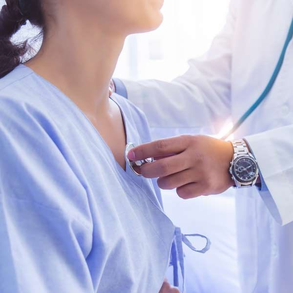 A doctor is listening to a patient 's heartbeat with a stethoscope representing Cardiovascular Support Treatments
