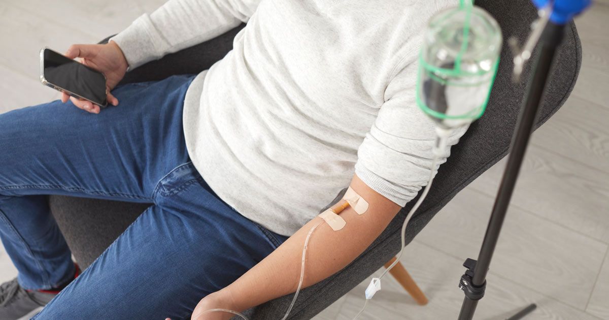 A man is sitting in a chair with an IV in his arm getting Chelation Therapy NYC by Dr. John Salerno