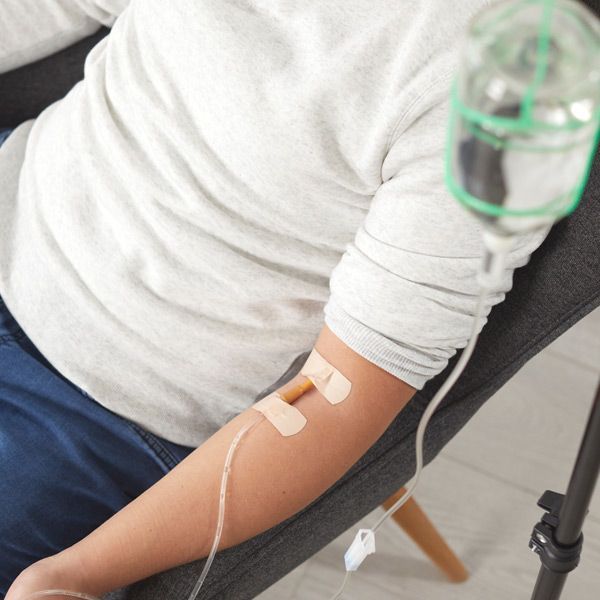 A person in a chair with an iv in their arm receiving Chelation Therapy