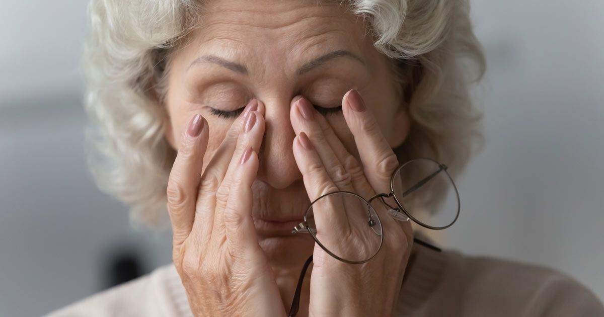 An elderly woman wearing glasses is rubbing her eyes representing Chronic Fatigue Syndrome Treatments NYC - Dr. John Salerno