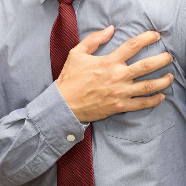 A man in a tie is holding his chest in pain. He has to start Congestive Heart Failure (CHF) IV Treatments