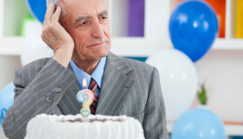 An elderly man with Alzheimer’s disease, displaying a blank expression, holds his head.