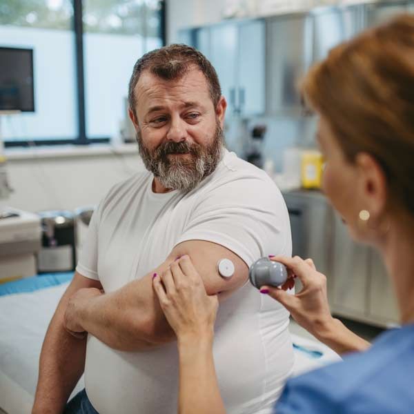 A man with a beard is getting a glucose monitor installed, which is part of Comprehensive Integrative and Functional Diabetes Management by Salerno Wellness in Manhattan, NY, and Connecticut
